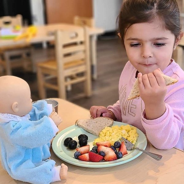 Girl Eating with Doll